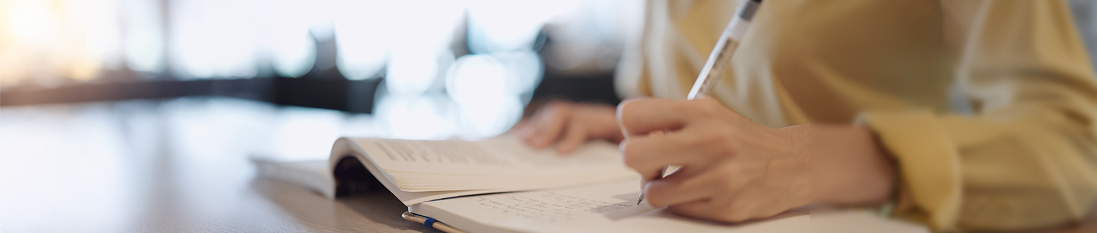 close up of student writing in notebook with a pen.