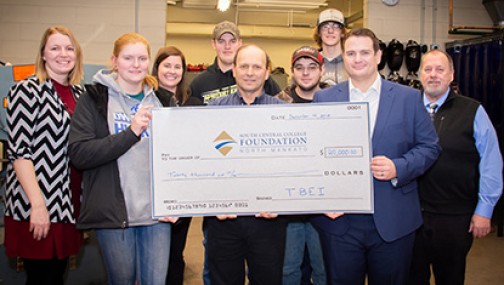 Group of student, faculty, administrators, and industry partners holding a very large donation check for scholarships