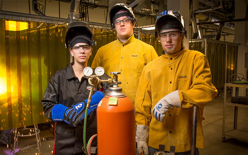 SCC student in welding gear working in a lab setting