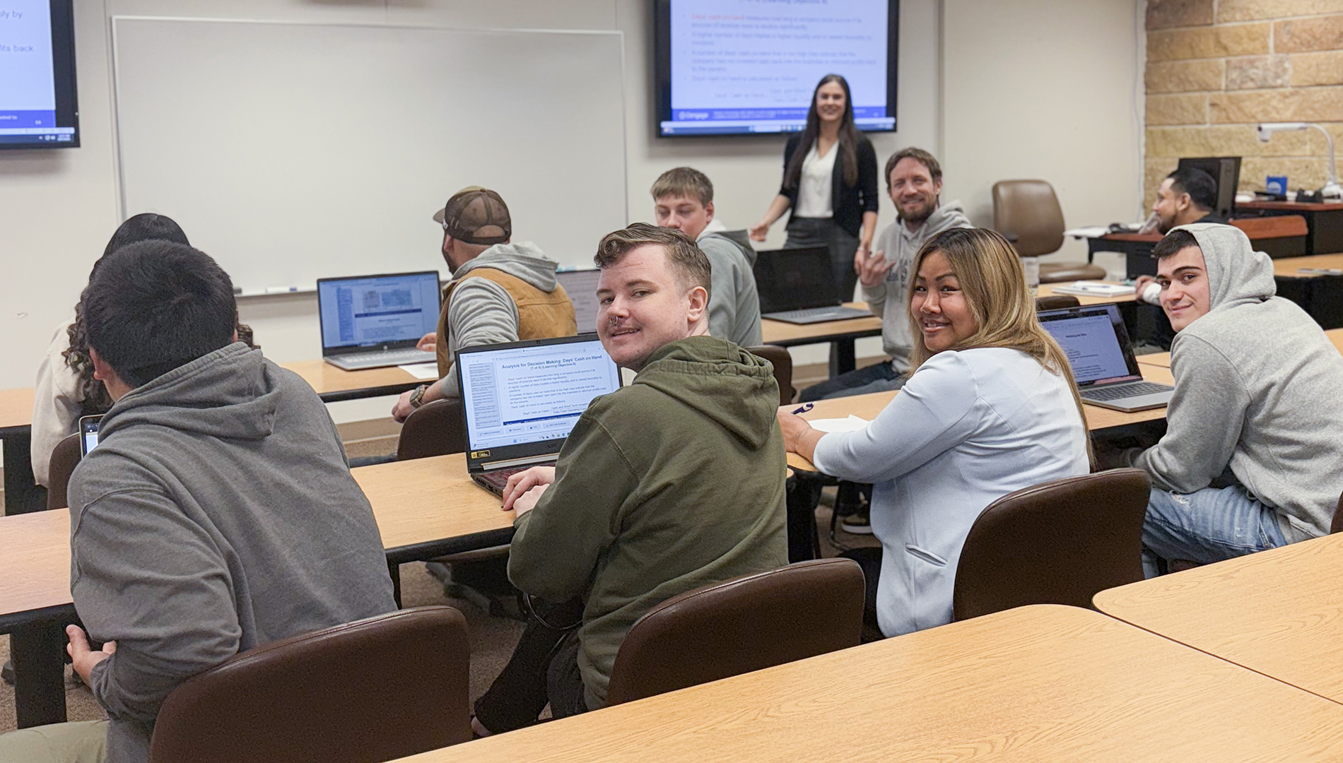 Students and instructor in classroom smiling at camera