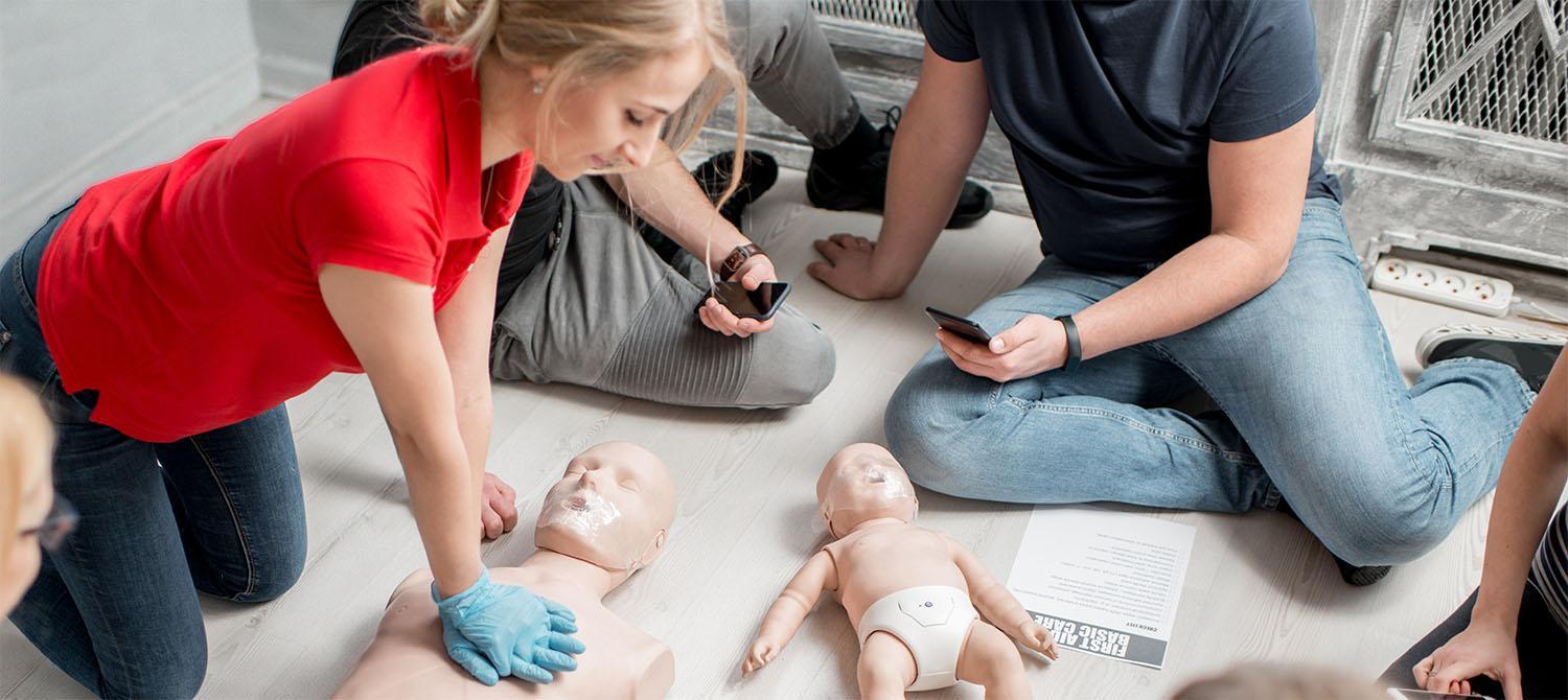 Students in CPR training class performing CPR on adult and infant mankins
