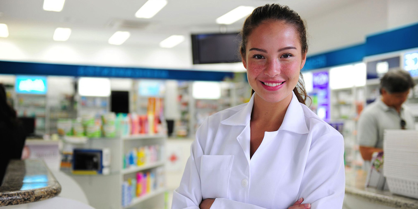 Photo of young female pharmacy technician in the workplace smiling at camera