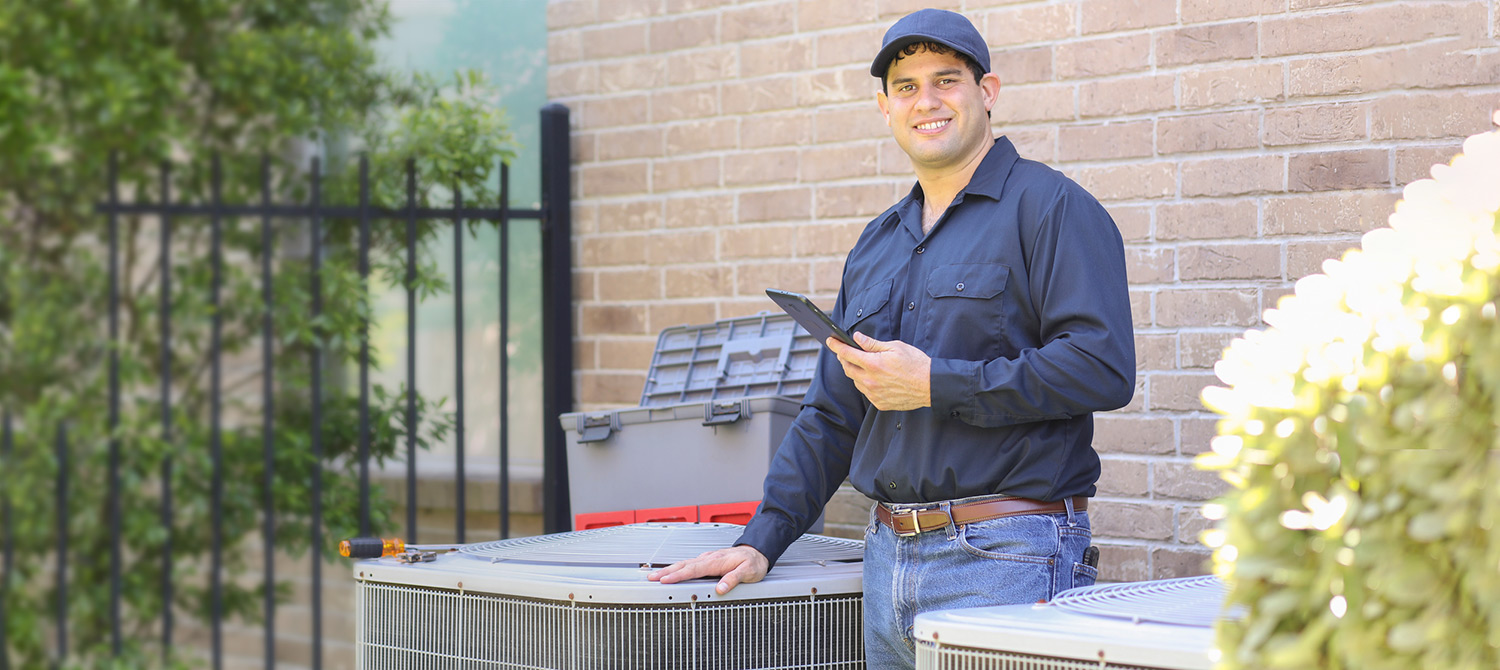 HVACR technician standing by outside residential air conditioning units