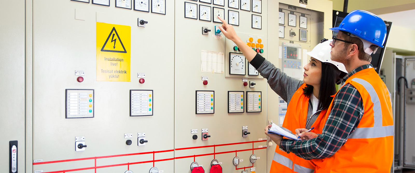 Maintenance workers interacting with electrical panel at an industrial job site.