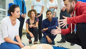 Trainees circled around a CPR simulator with instructor