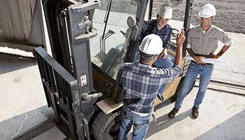 Instructor standing with students around a forklift