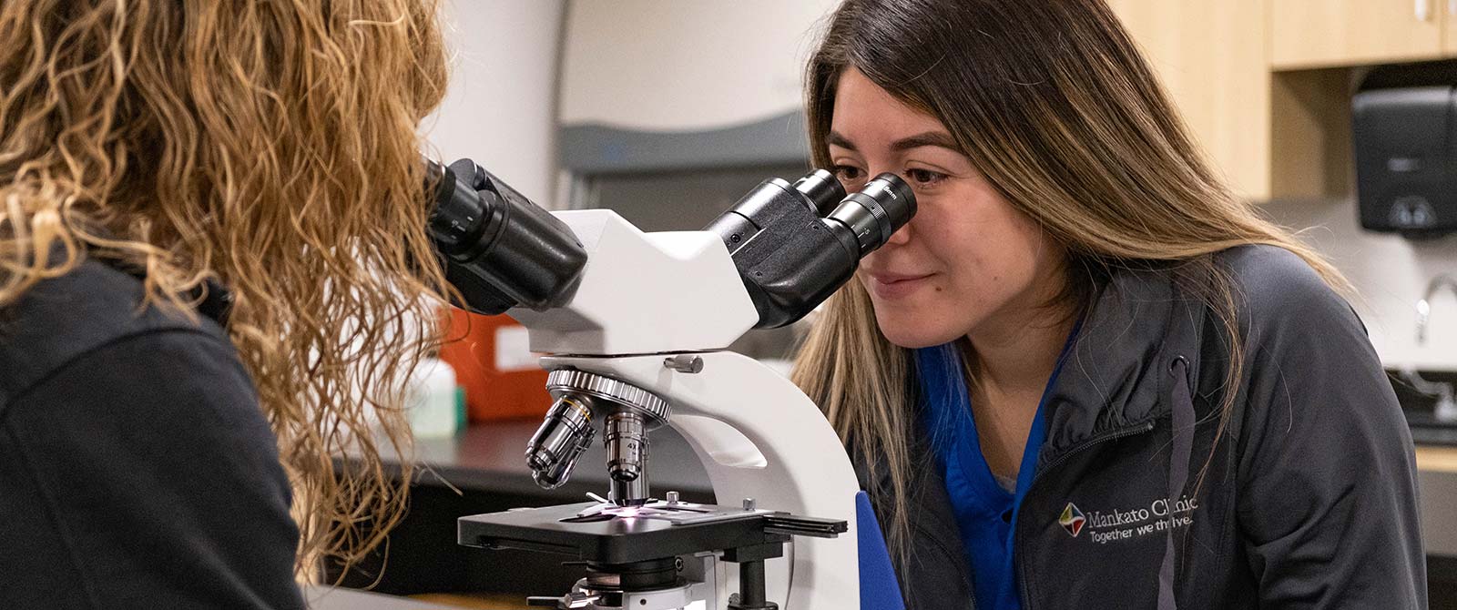 Two students in lab looking through a microscope